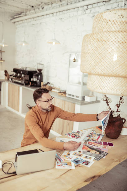 Fashion designer looking at pictures with his dresses.