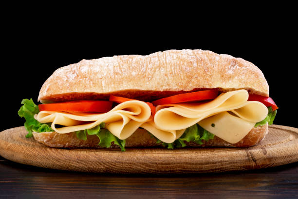 istock Ciabatta sandwich with lettuce , prosciutto and  cheese on wooden board 1151016446
