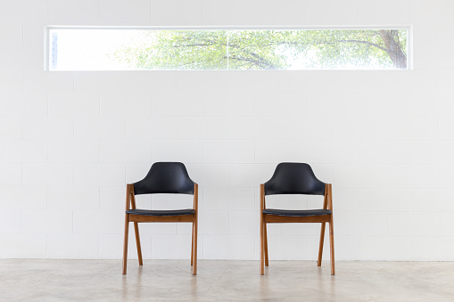 front view of two wooden leather chair on white brick wall background.