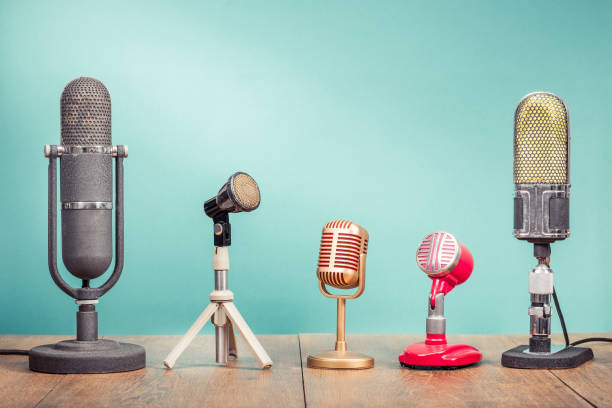 istock Retro old microphones for press conference or interview recording on wooden table front gradient aquamarine wall background. Vintage old style filtered photo 1151021128
