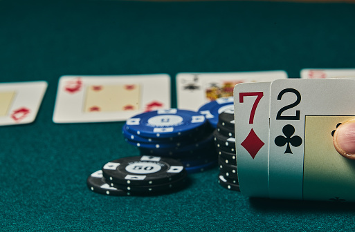 Bad poker gamble or unlucky hand concept with player going all in with 2 and 7 (two and seven) offsuit also called unsuited, considered the worst hand in poker preflop (before the flop is revealed)