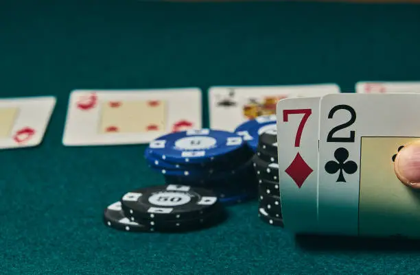 Photo of Bad poker gamble or unlucky hand concept with player going all in with 2 and 7 (two and seven) offsuit also called unsuited, considered the worst hand in poker preflop (before the flop is revealed)