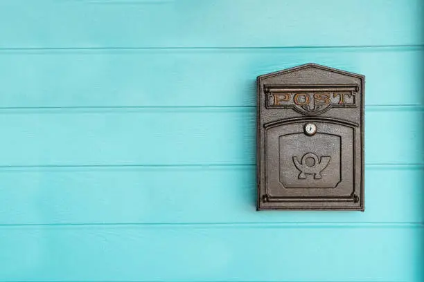 Photo of postbox hanging on a blue wood wall