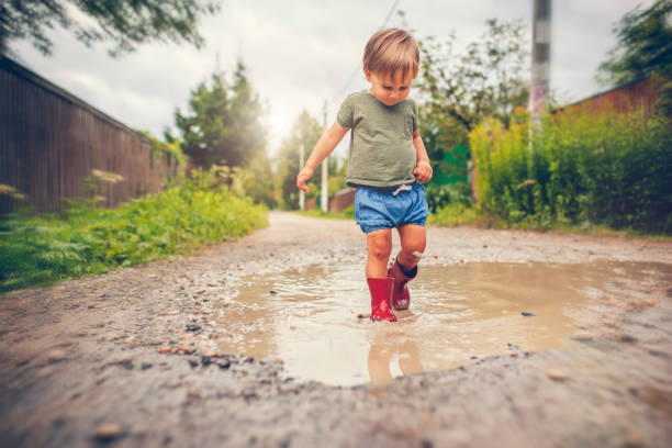 istock Little boy playing in puddle in a rainy day 1151043093