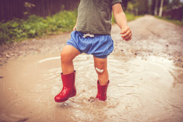 istock Little boy playing in puddle in a rainy day 1151043104