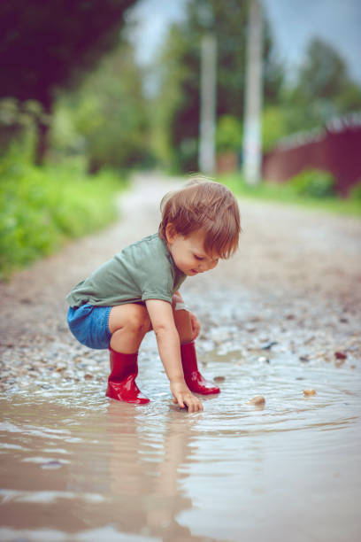 istock Little boy playing in puddle in a rainy day 1151043113