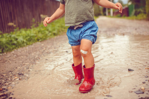 istock Little boy playing in puddle in a rainy day 1151043116