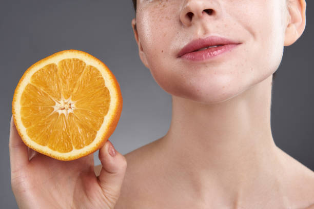 istock Smiling young woman holding fresh orange half 1151045689