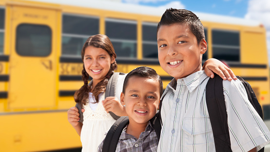 Jóvenes hispanos y chicas que caminan cerca del autobús escolar photo
