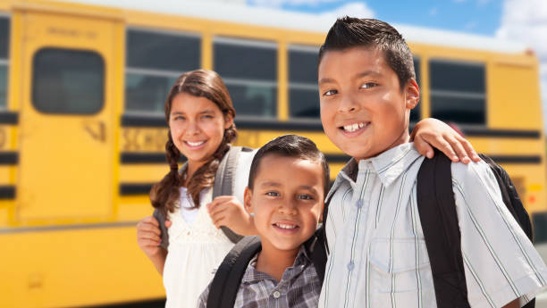jeunes hispaniques garçons et fille marchant près de l’autobus scolaire - ibérique photos et images de collection