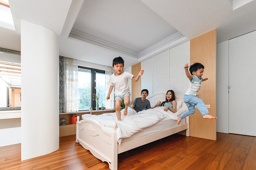 Energetic Taiwanese boys jumping off their parent's bed in the morning.