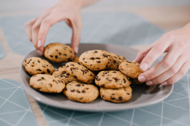 istock Hands take fresh cookies from plate, close-up 1151054244