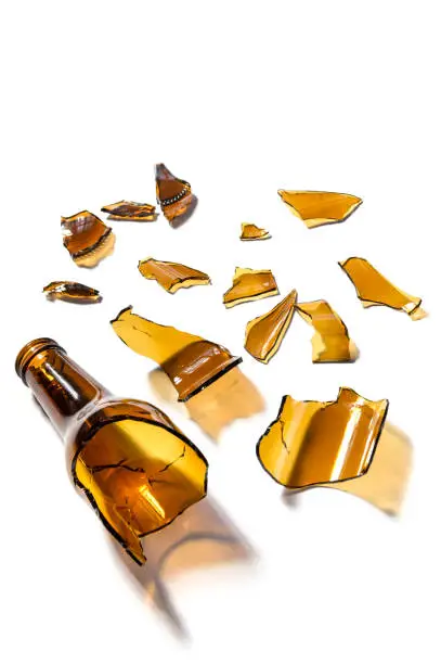 Photo of Glass beer bottle broken in half isolated on white background. Opaque glass bottle of brown color broken in pieces and cracked. Improvised weapon.