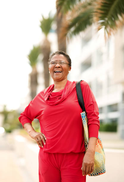 I'm in the best phase of my life Portrait of senior woman in red dress standing outdoors and laughing older woman purse stock pictures, royalty-free photos & images