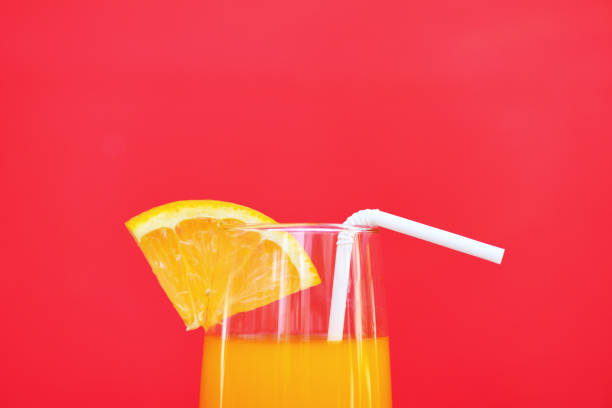 istock Orange juice summer glass with piece orange fruit on red background 1151077293