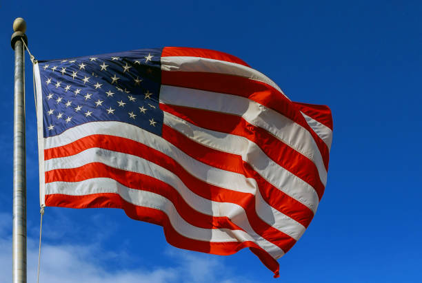 slight motion blur american flag against a blue sky with clouds - american flag star shape striped fourth of july imagens e fotografias de stock