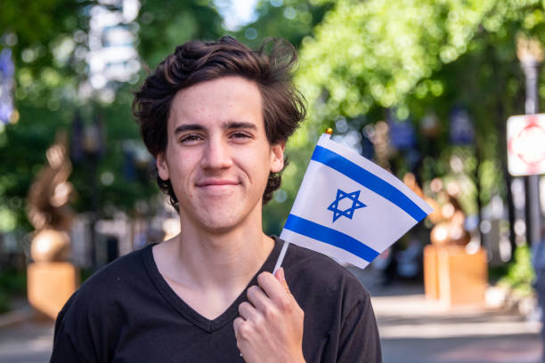 jeune homme souriant agitant le drapeau israélien - israelite photos et images de collection