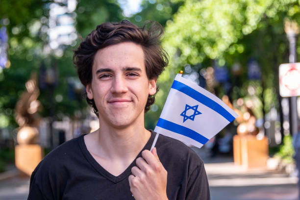 Smiling young man waving the Israeli flag Smiling young man waving the Israeli flag looking at the camera israeli flag photos stock pictures, royalty-free photos & images