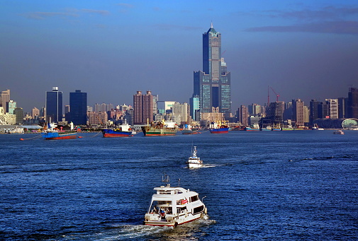 KAOHSIUNG, TAIWAN -- DECEMBER 22, 2018: Tourist boats take visitors on a cruise across Kaohsiung Port. In the back is the skyline of the city.