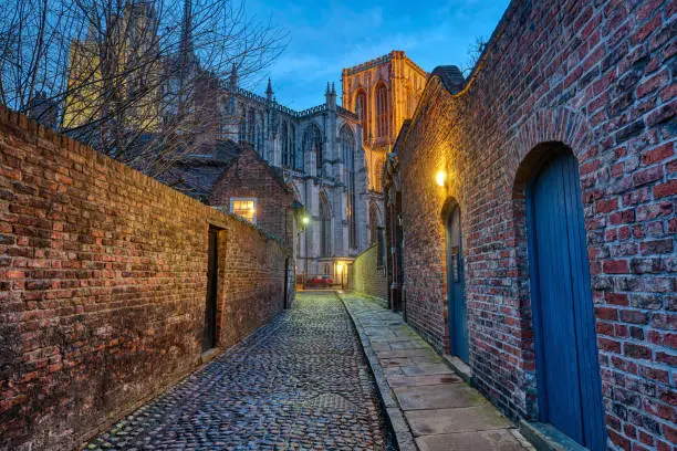 Small cobbled alleyway in York at night with the famous Minster in the back