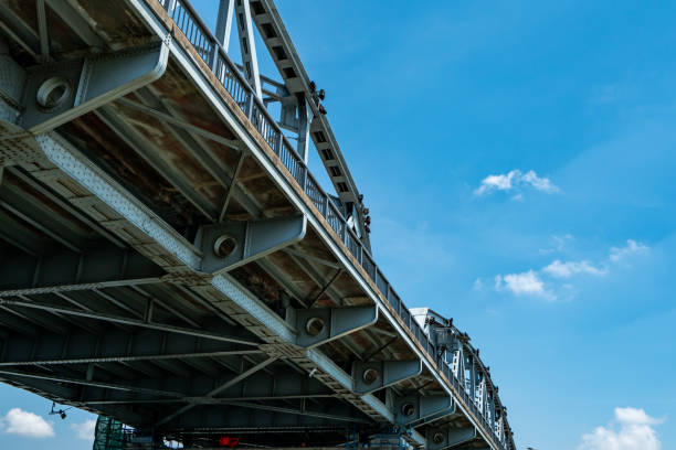 Steel bridge structure against blue sky and white clouds. Iron bridge engineering construction. Strong and strength metal bridge. Road bridge architecture. Infrastructure.