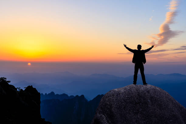 istock Hiker is standing on a rock with raised hands and enjoying sunrise 1151101933