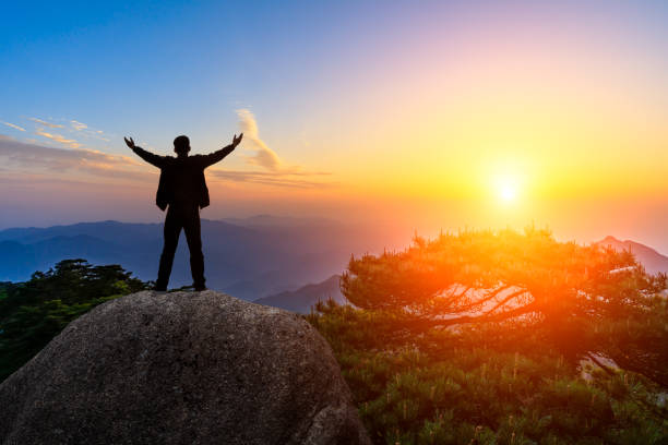 istock Hiker is standing on a rock with raised hands and enjoying sunrise 1151101940