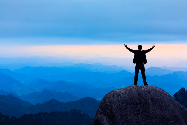 istock Hiker is standing on a rock with raised hands and enjoying sunrise 1151102013