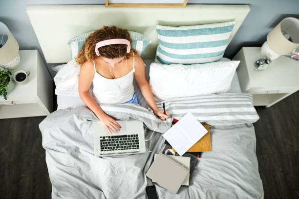 Early birds have productivity based mornings High angle shot of a young woman using a laptop while studying in bed in the morning image based social media photos stock pictures, royalty-free photos & images
