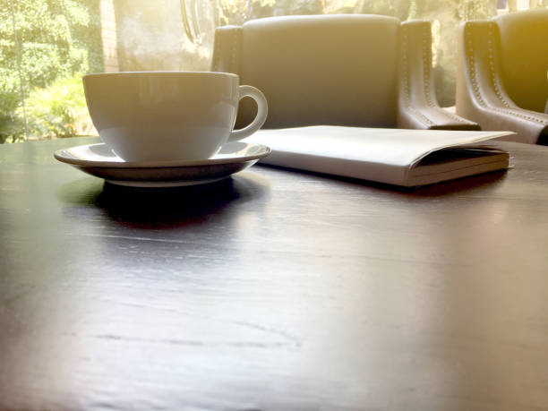istock Afternoon tea in white cup with notebook on brown wooden table in the cafe. 1151104478