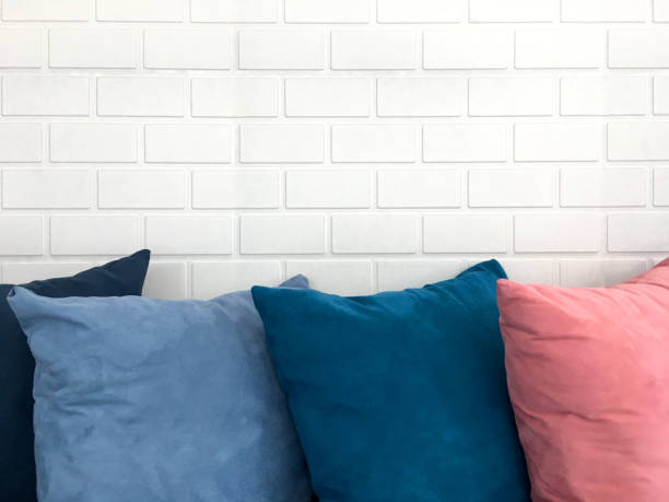 istock Colorful decorative resting pillow stack on sofa in front of white brick background. 1151104603