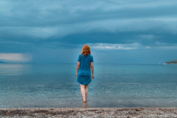 femme rousse marchant dans la mer dans une robe bleue - 7679 photos et images de collection