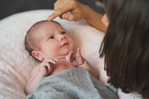 Happy mother giving cuddles and playing smiling with her cute newborn. Family, new life, childhood, beginning concept.