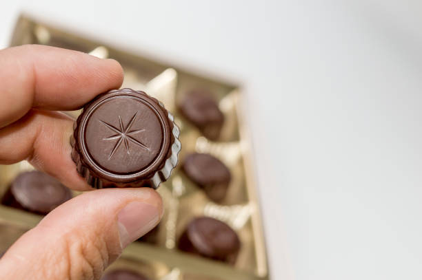 チョコの箱からチョコレートを持っている男の手。 - chocolate box human hand giving ストックフォトと画像