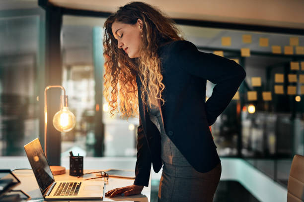 I'll have to go home... Shot of a businesswoman suffering from back pain while sitting at her desk office back pain stock pictures, royalty-free photos & images