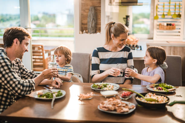 istock Young happy family toasting during lunch time at dining table. 1151112974