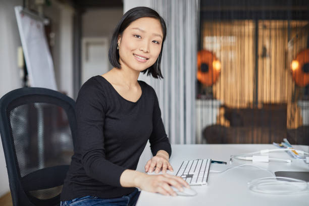 istock Smiling and looking at camera sitting down on her desk. New business office. 1151114503