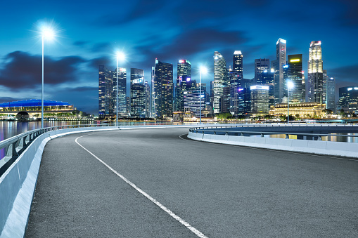 High speed corner overpass asphalt road with Singapore cityscape , night scene .