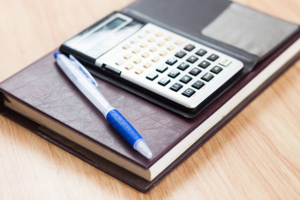 istock Close-Up Of Calculator And Book On Table 1151130299