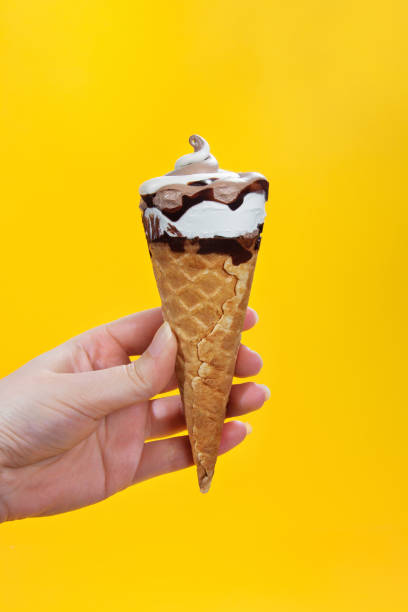 istock chocolate cream ice cream in waffle cone on yellow background. 1151135624