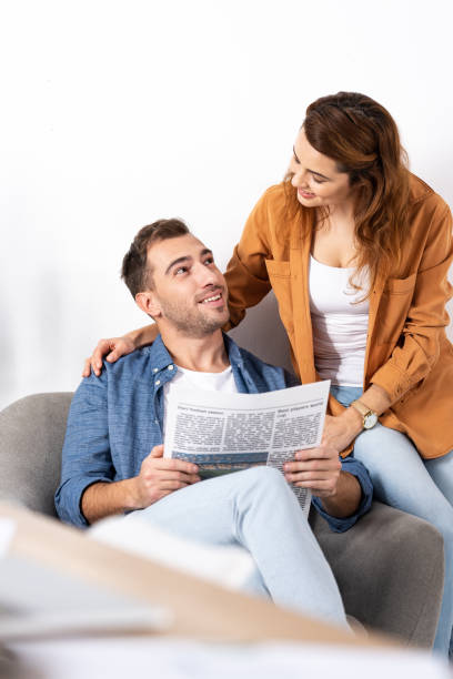 istock cheerful woman hugging and looking at man with newspaper 1151137791