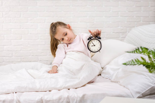 istock Little girl in pyjamas with clock 1151137868