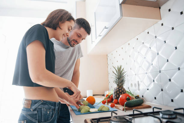 istock Nice looking interior. Young couple in the modern kitchen at home at their weekend time in the morning 1151140104