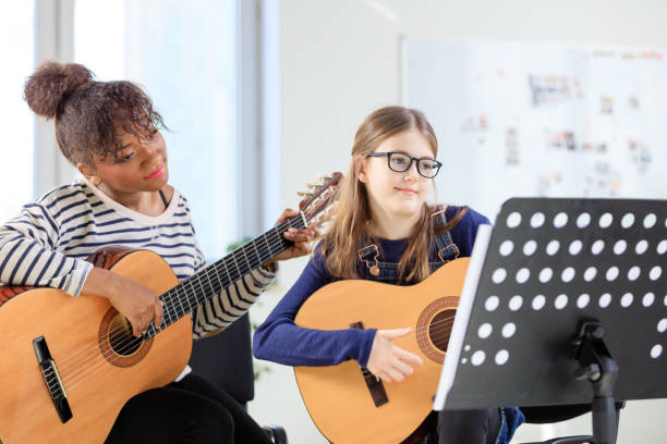 istock Guitarist looking at sheet with girl in class 1151140370