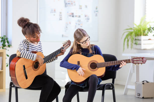 istock Guitarist teaching female student plucking guitar 1151140521