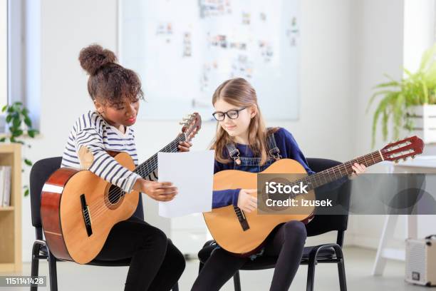 Music Trainer Showing Sheet To Female Student Stock Photo - Download Image Now - Child, Classroom, African-American Ethnicity
