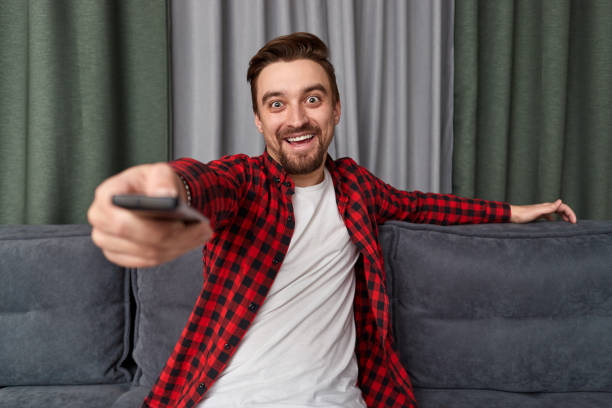 istock Cheerful man with remote control watching movie 1151141489