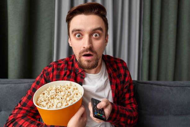 istock Shocked man with popcorn watching scary movie 1151141508