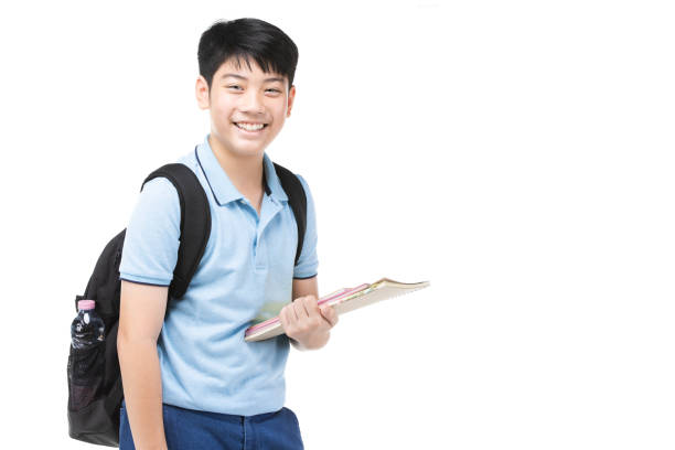 Portrait of smiling little student boy in blue polo t-shirt in with books and bag over white background - school, education and people concept stock photo