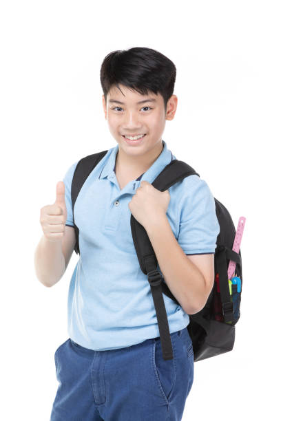 Portrait of smiling little student boy in blue polo t-shirt in with books and bag over white background - school, education and people concept stock photo